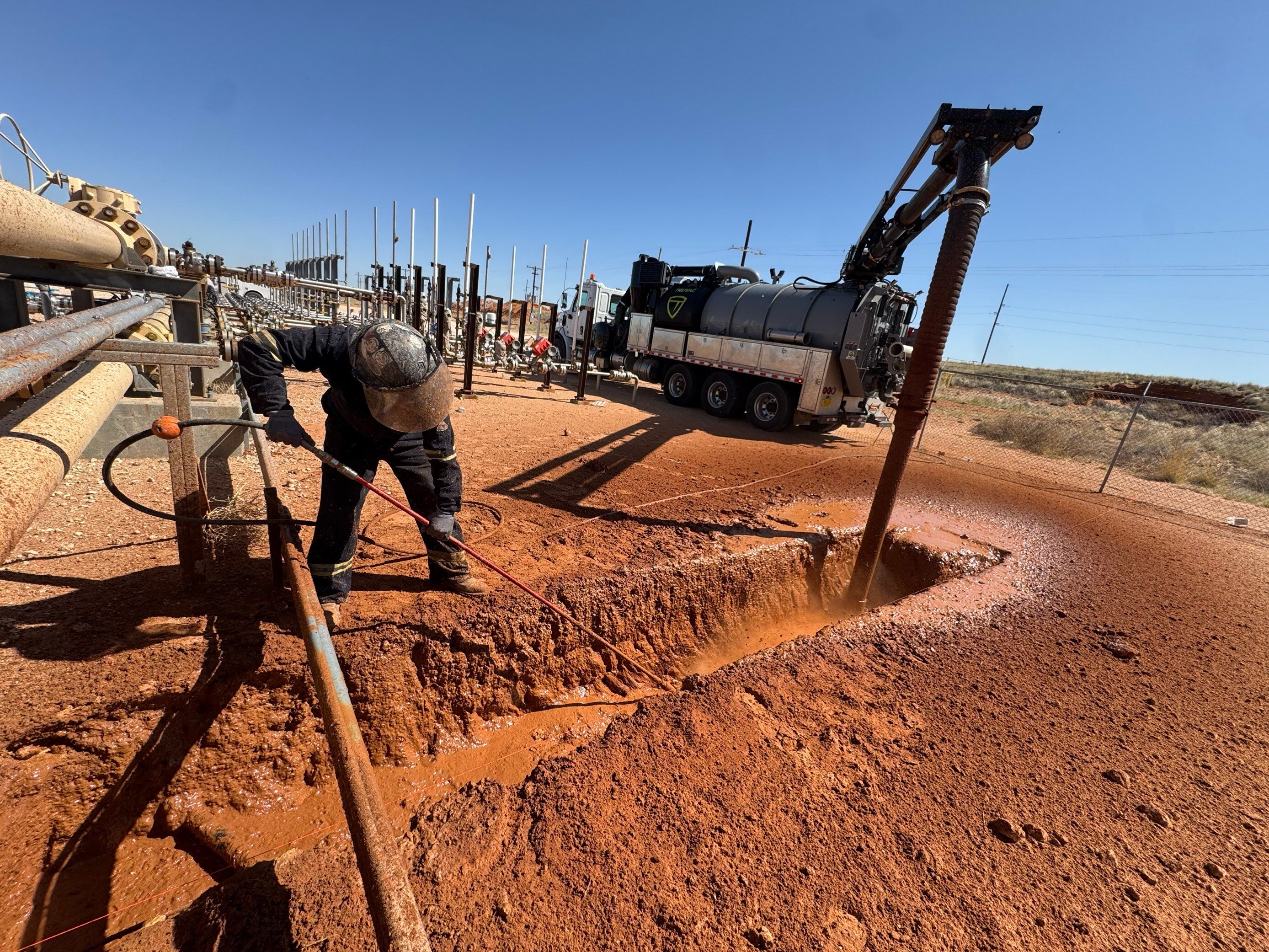 Someone digging with a hydroexcavtion wand, using a TRUVAC hydro vac truck